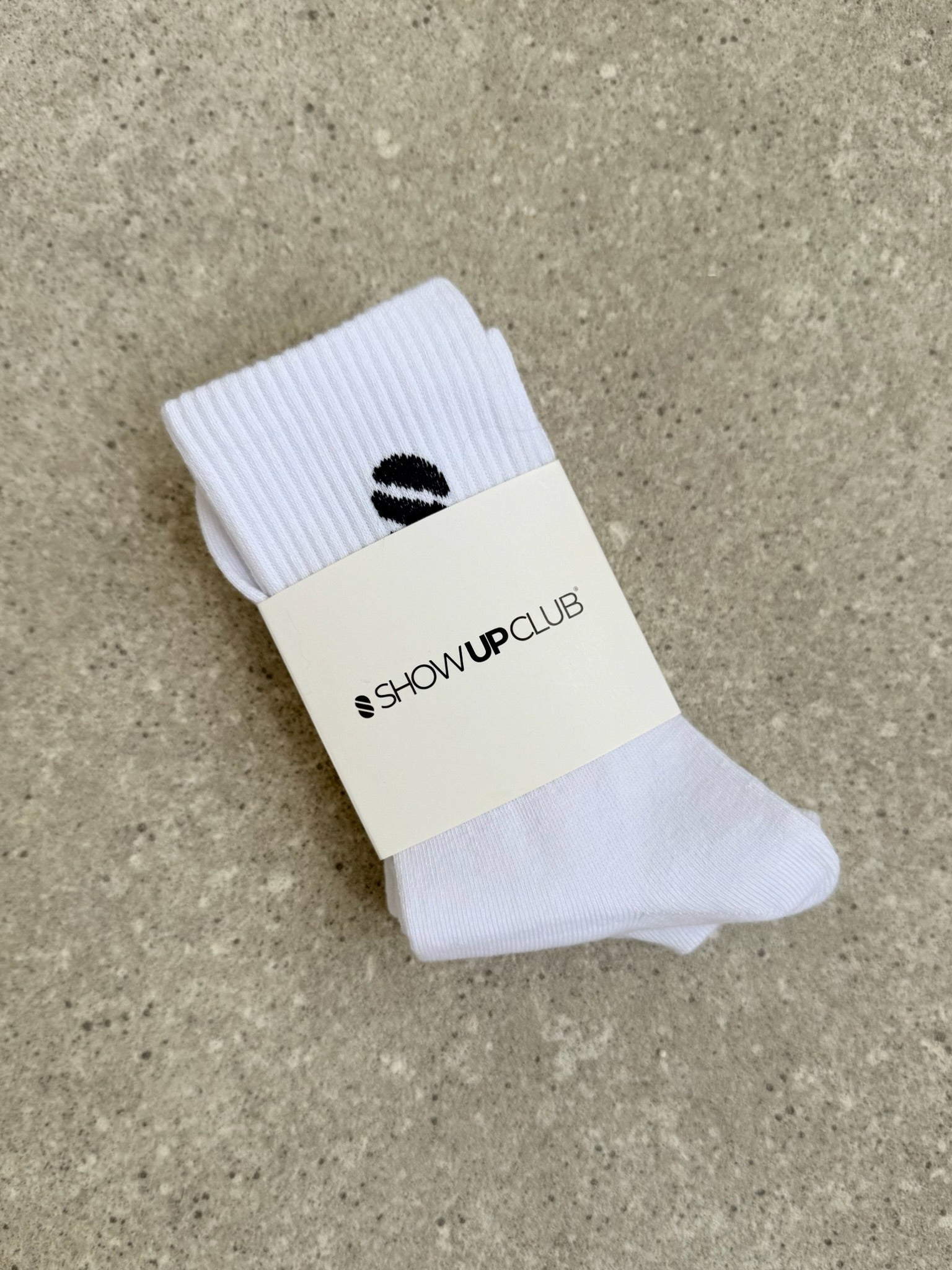White sock with a visible brand label on a beige surface.