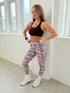 Woman in athletic wear standing in a room with large windows.