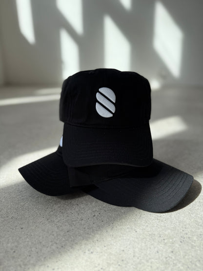 Black pile of caps with a logo on a light surface with shadows