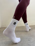 White socks with a navy logo worn by a person against a neutral background